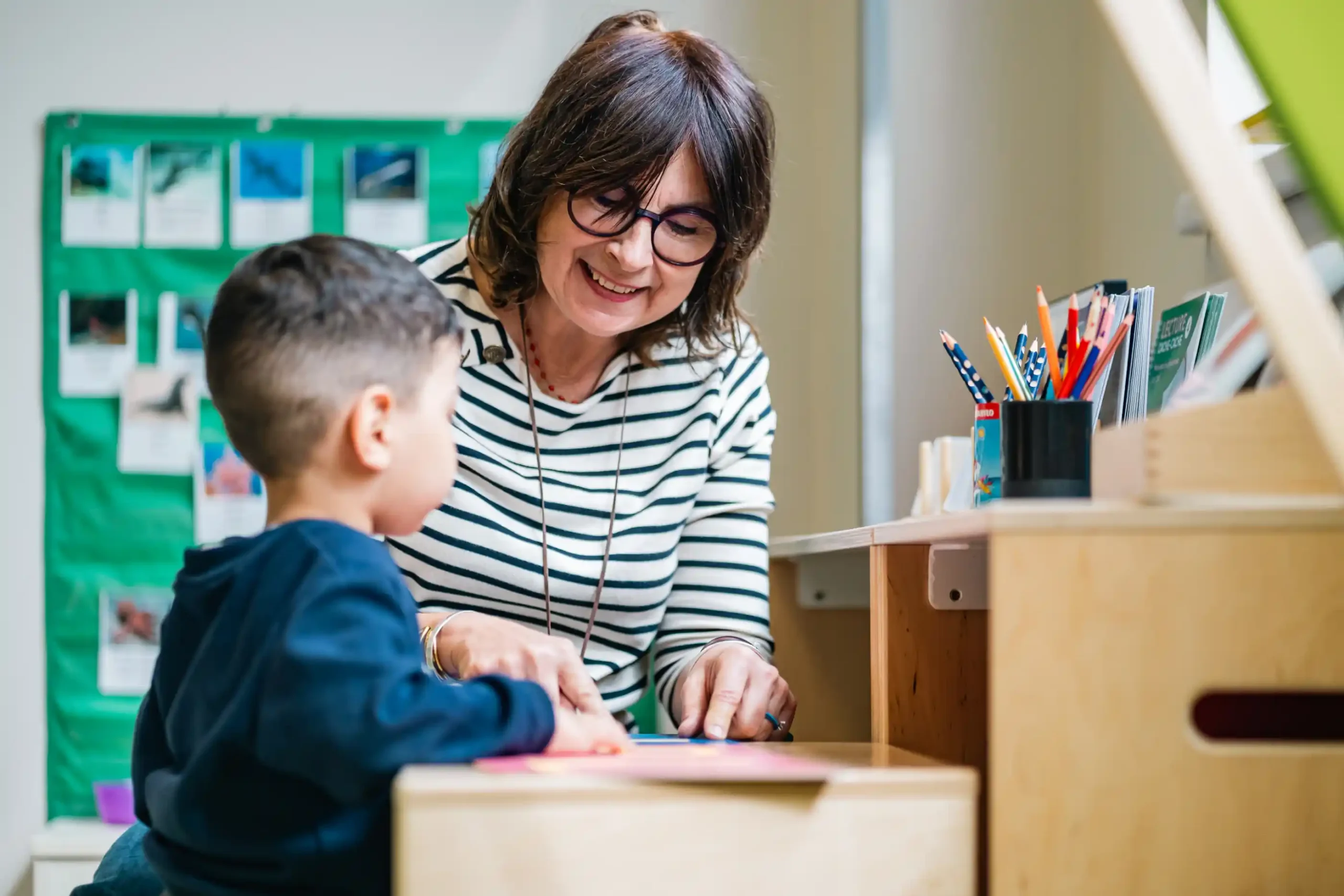 Une enseignante accompagne un élève de maternelle en atelier