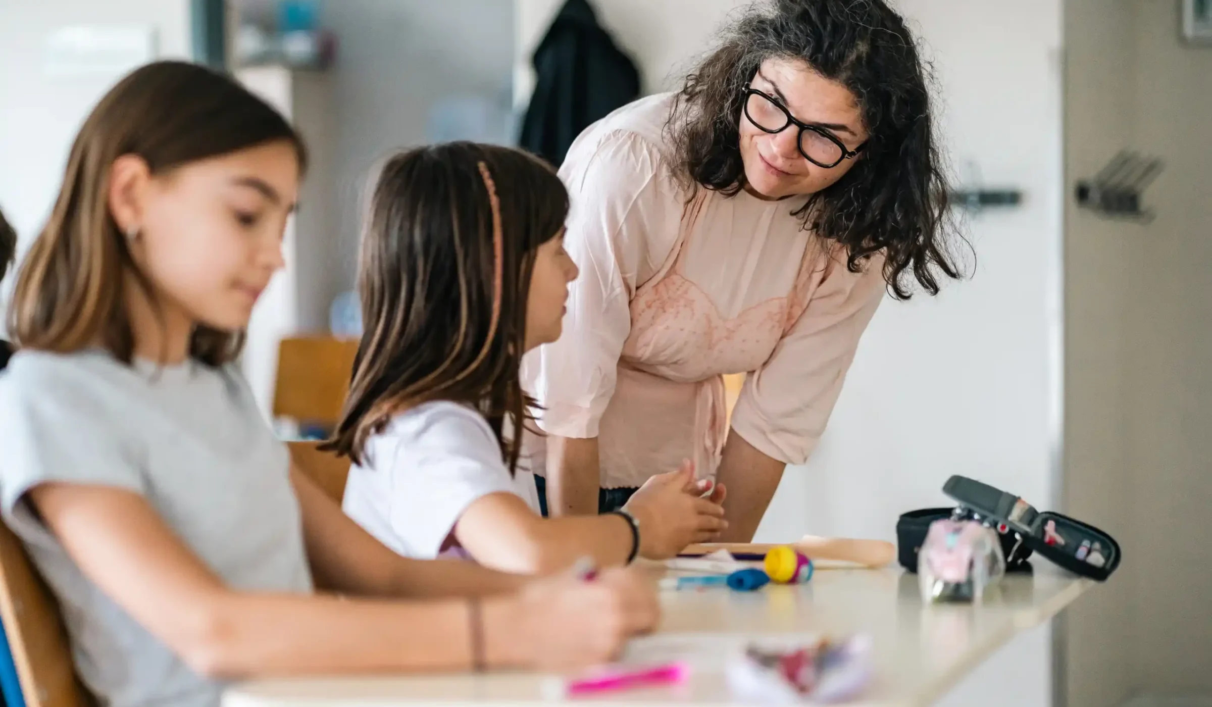 Une enseignante accompagne deux élèves de l'élémentaire en atelier
