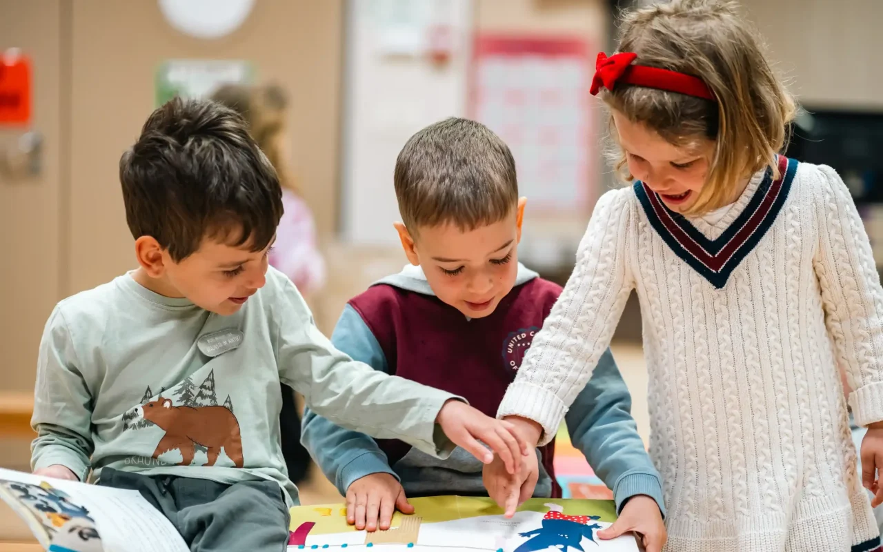 Trois élèves de maternelle peignent ensemble en atelier d'arts plastiques