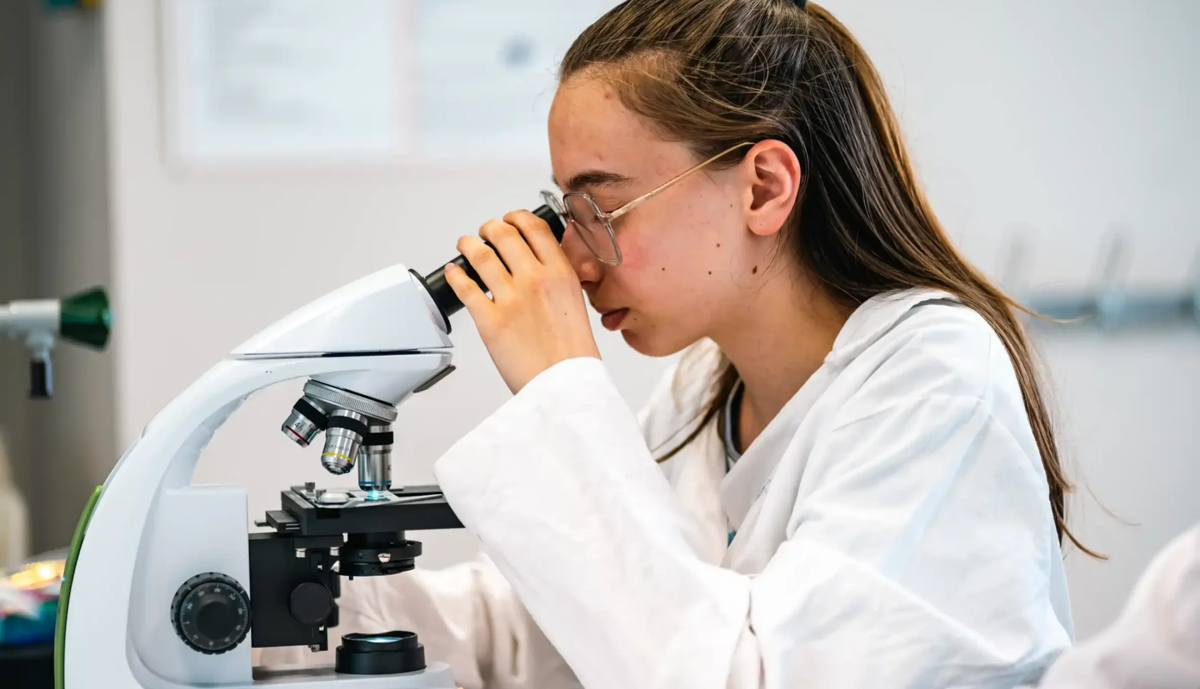 Une élève de lycée observe un échantillon au microscope