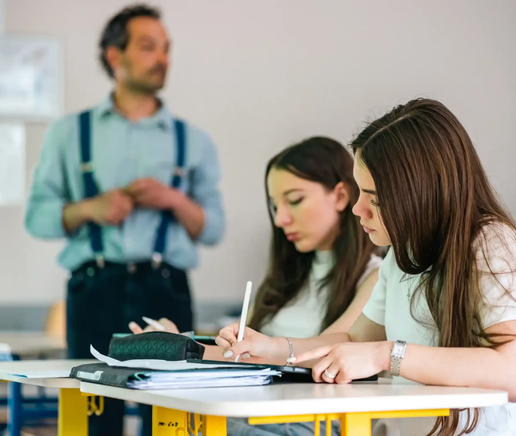 Un enseignant accompagne deux élèves à leur table