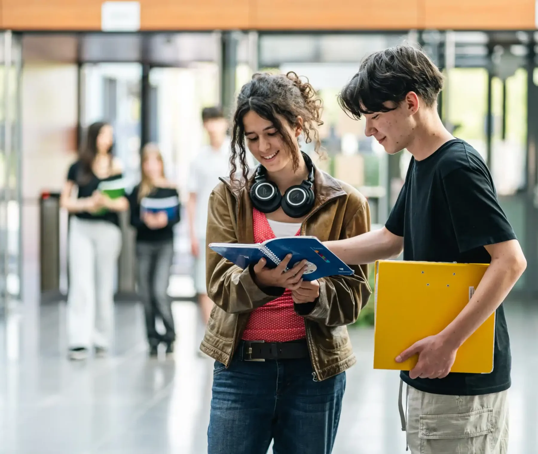 Des élèves discutent dans le hall du lycée, dossiers à la main