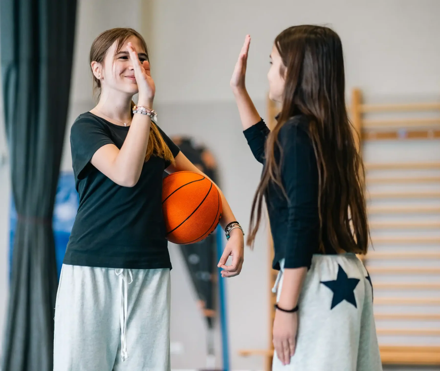 Deux élèves de l’Association Sportive se félicitent au gymnase, ballon de basket en main